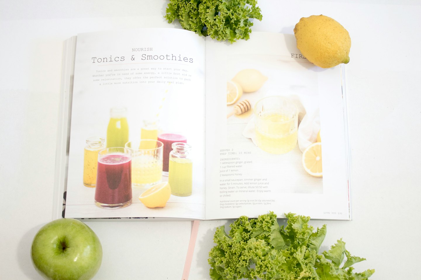 Open cookbook with fresh ingredients for healthy drinks.